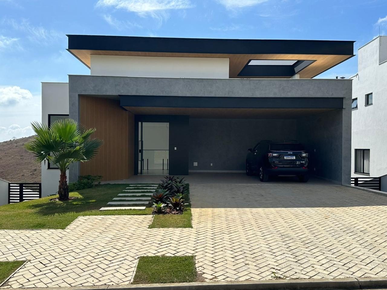 Residência com forro de madeira na entrada, garagem coberta e paisagismo com palmeira
