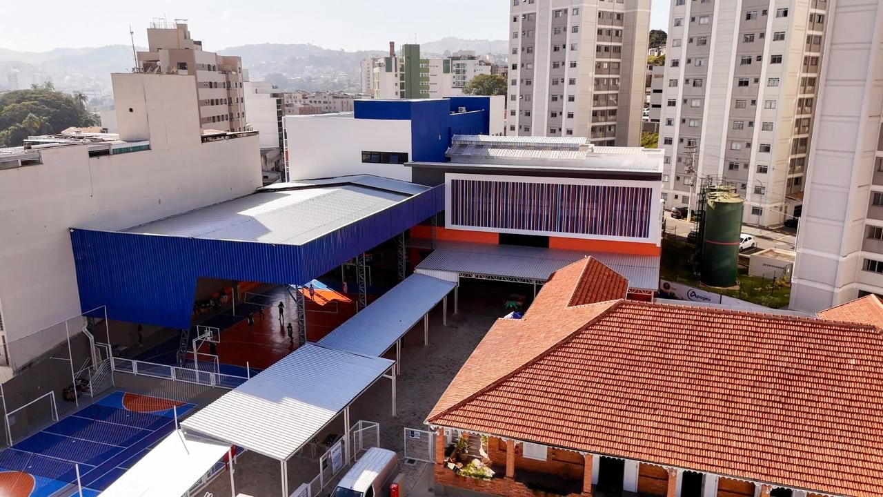 Edifício comercial com fachada em painéis azuis e brancos, visto do alto entre prédios vizinhos