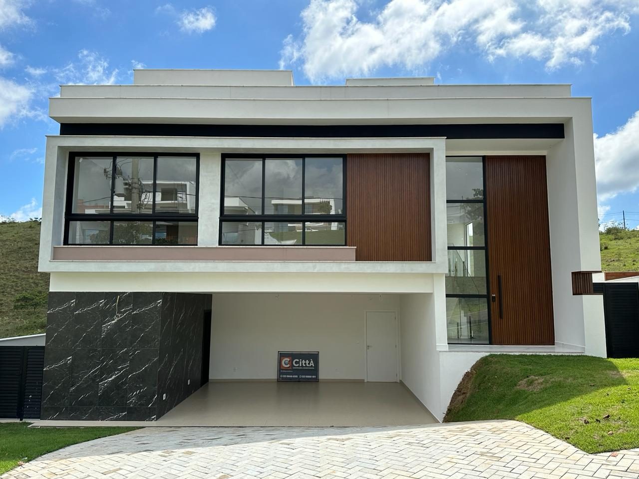 Fachada de residência com revestimento em pedra escura, madeira e grandes esquadrias