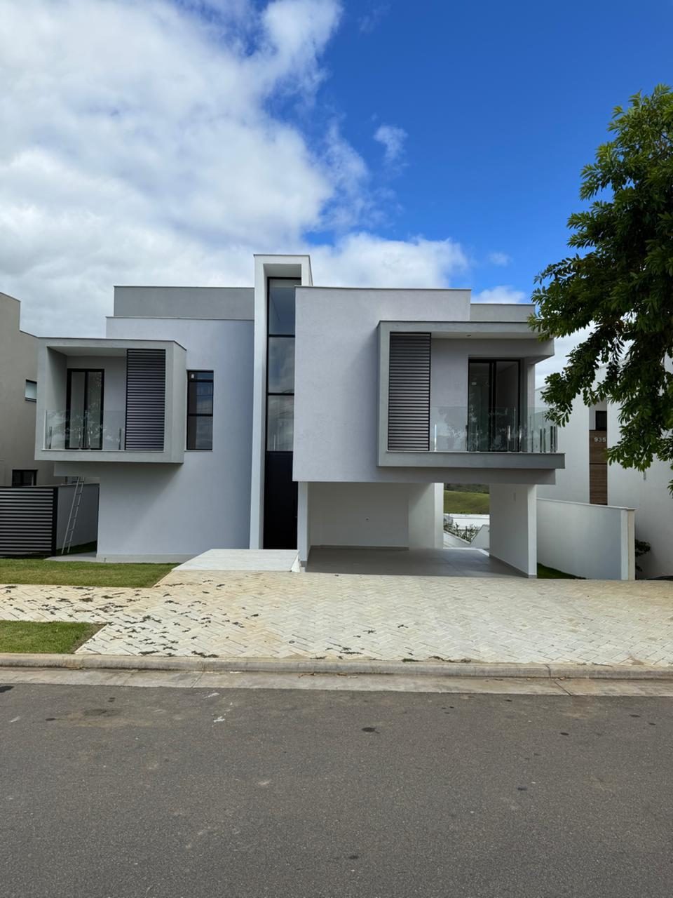 Residência branca de dois pavimentos com volumes recuados e janelas em fita