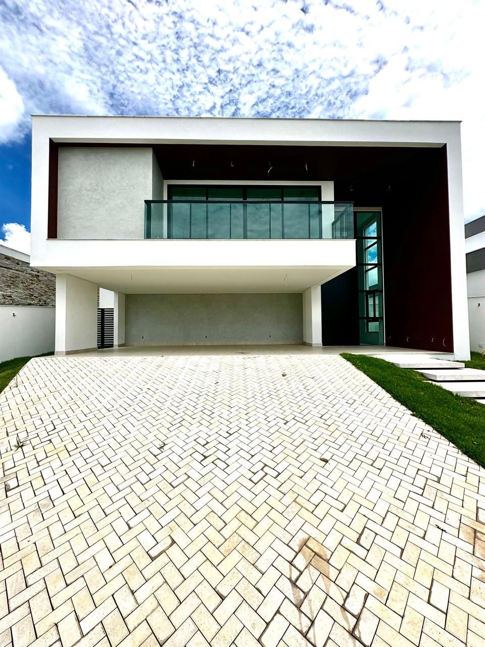 Fachada de residência de dois pavimentos com varanda em vidro e grande acesso em pedra portuguesa